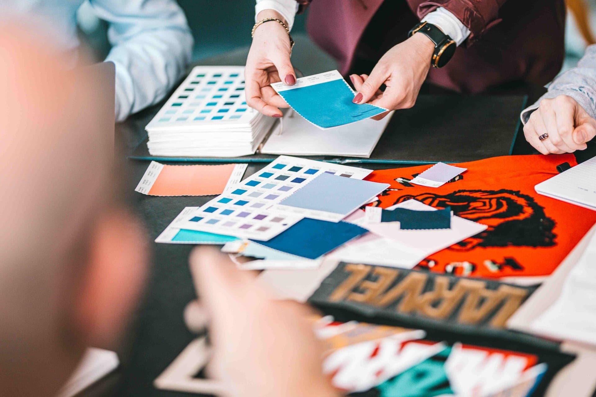 Hands comparing fabric colour swatches next to a garment with a Marvel print