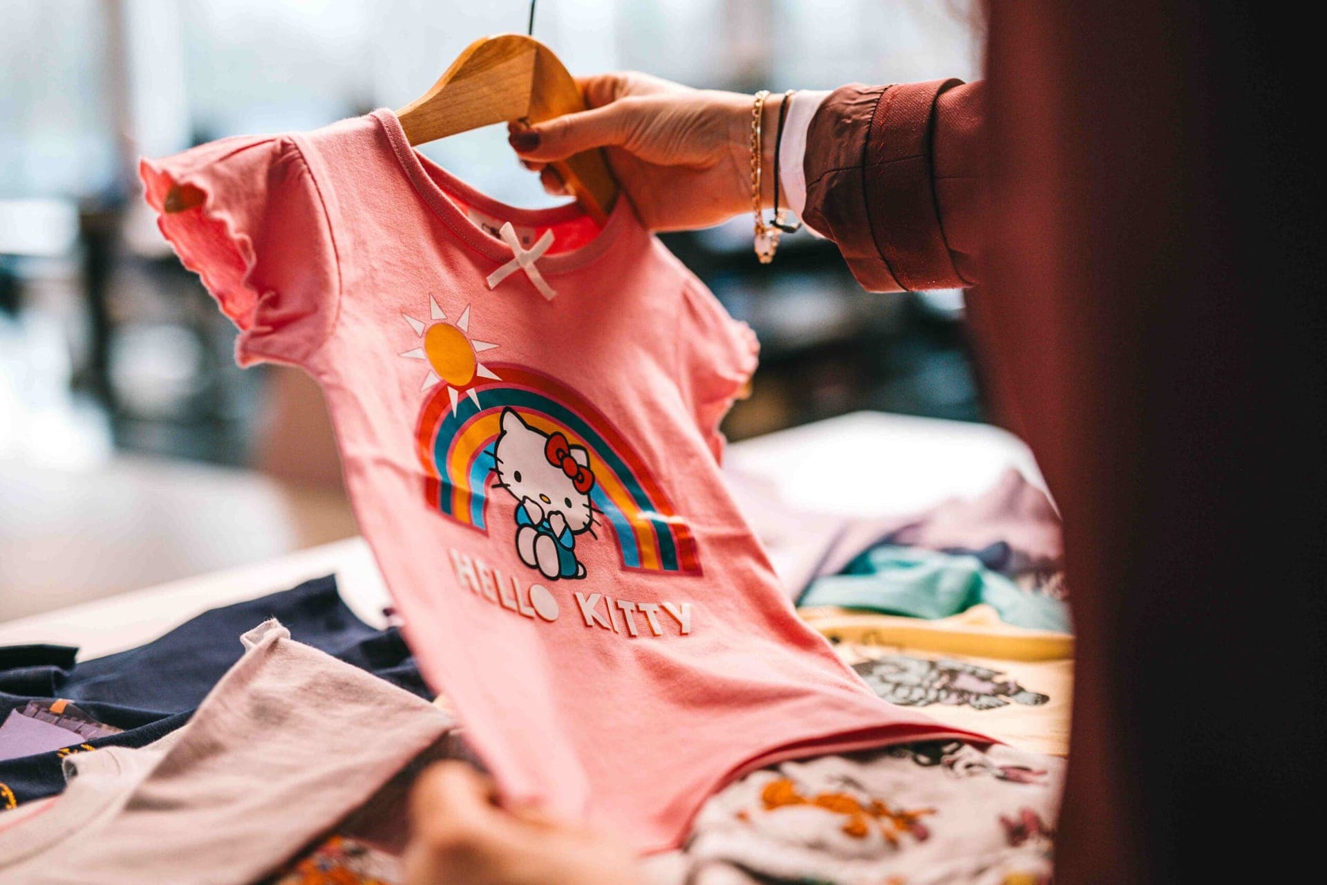 Pink Hello Kitty t-shirt with a rainbow print on a hanger
