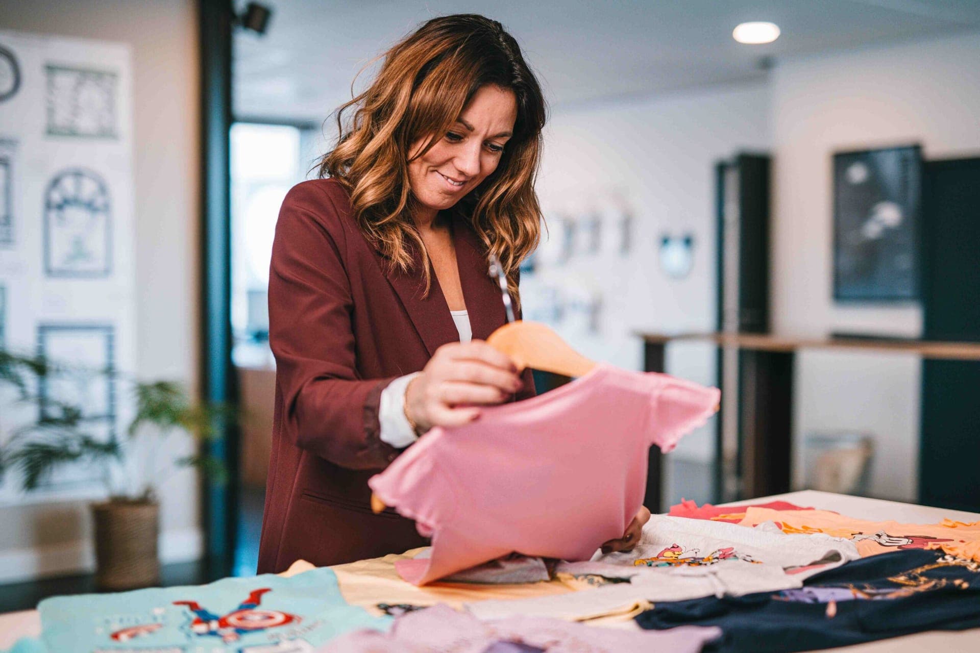 Colleague choosing a pink t-shirt from a table full of licensed kids' t-shirts